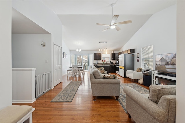 living room with hardwood / wood-style flooring, high vaulted ceiling, and ceiling fan with notable chandelier