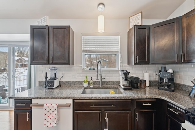 kitchen with dark brown cabinetry, sink, dark stone counters, and decorative backsplash