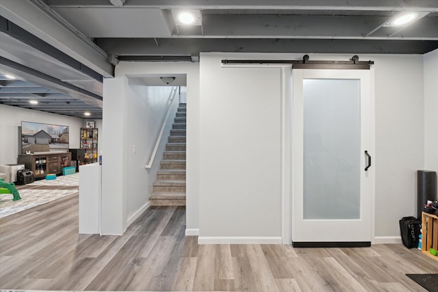 basement featuring light hardwood / wood-style floors and a barn door