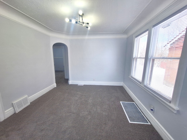 spare room featuring a textured ceiling and dark carpet