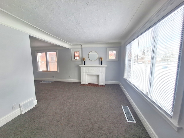 unfurnished living room featuring dark colored carpet and a textured ceiling