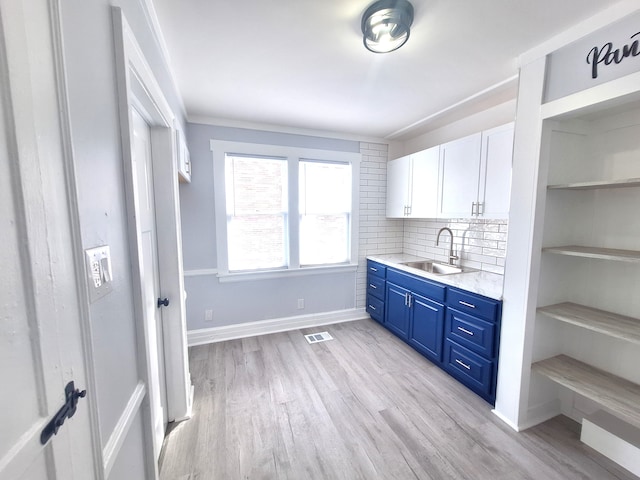 bar featuring sink, light hardwood / wood-style flooring, white cabinetry, blue cabinets, and decorative backsplash