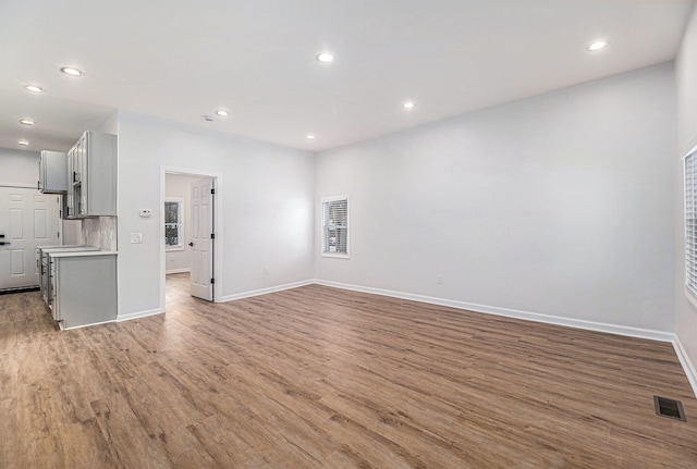 unfurnished living room with visible vents, recessed lighting, wood finished floors, and baseboards