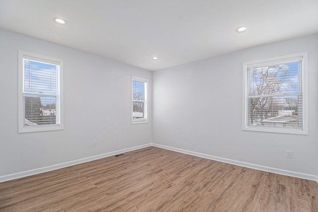 empty room with light wood finished floors, baseboards, and recessed lighting