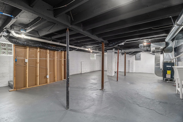 unfinished basement featuring electric panel and heating unit