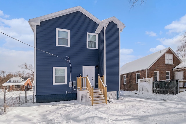 snow covered back of property with fence