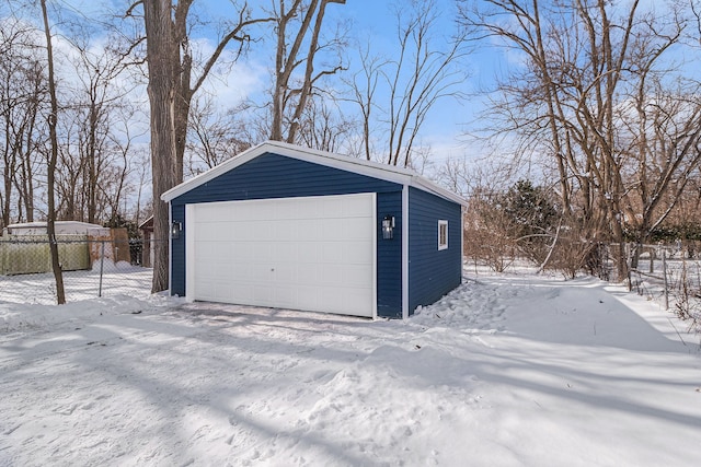 snow covered garage with fence and a garage