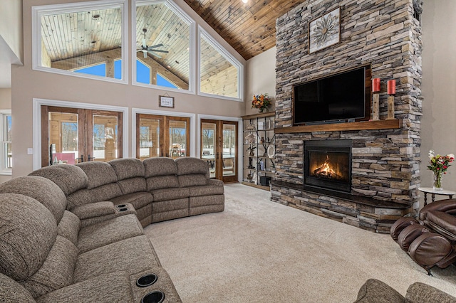 carpeted living area featuring french doors, a ceiling fan, high vaulted ceiling, a stone fireplace, and wood ceiling