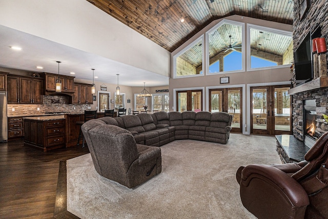 living room featuring ceiling fan, high vaulted ceiling, a stone fireplace, dark wood-style floors, and wood ceiling