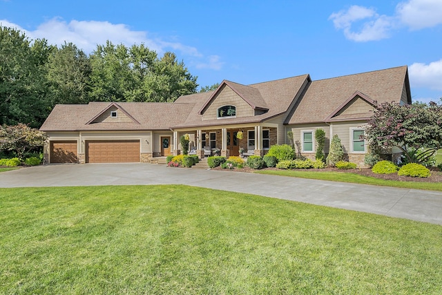 view of front of property with stone siding, a garage, concrete driveway, a front yard, and a porch