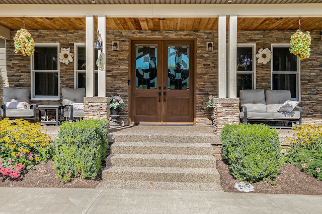 view of exterior entry with french doors and a porch