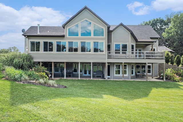 rear view of house featuring a shingled roof, a yard, and a patio area