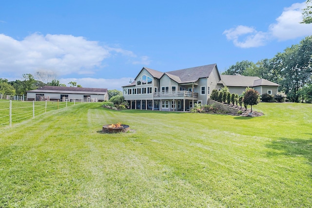 rear view of property with an outdoor fire pit, a yard, and fence