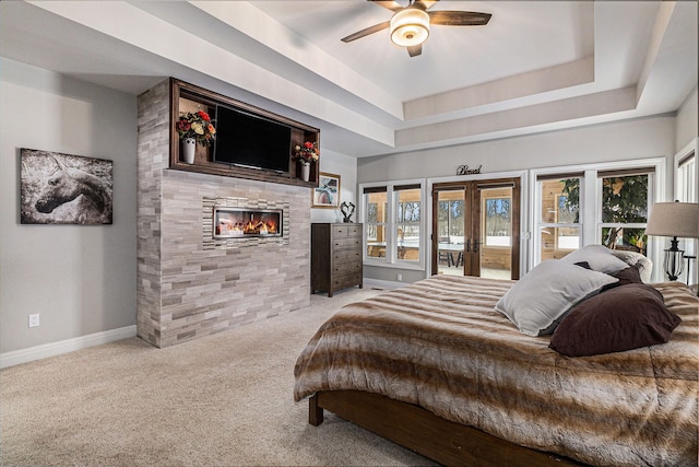 bedroom with french doors, light colored carpet, a raised ceiling, baseboards, and access to outside