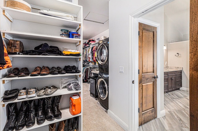 spacious closet with light wood-style flooring and stacked washer and dryer