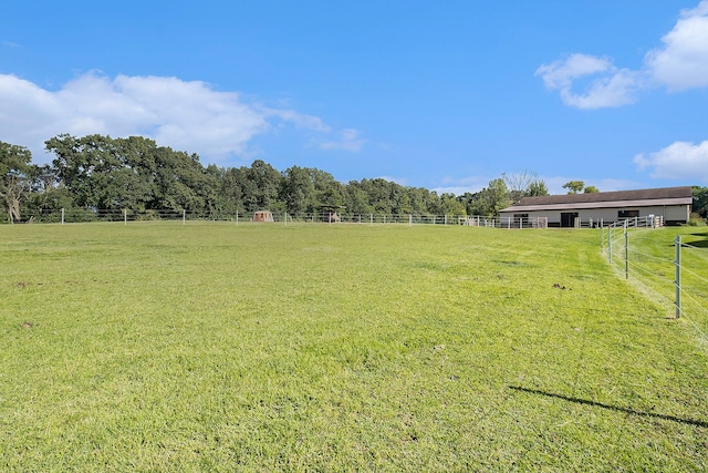 view of yard with fence and a rural view