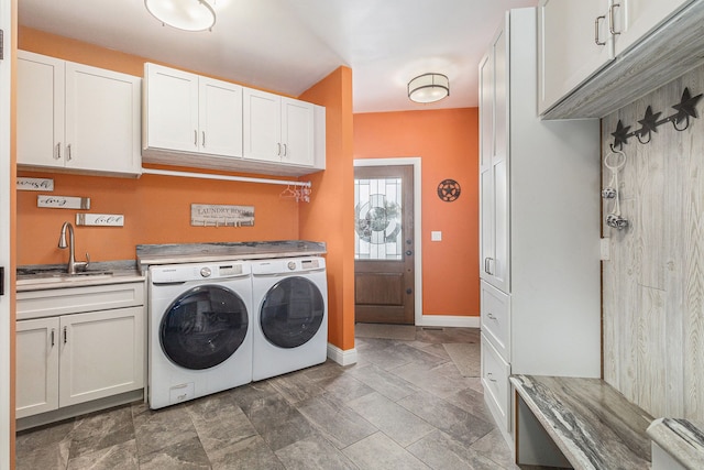 laundry area featuring a sink, baseboards, cabinet space, and washer and clothes dryer