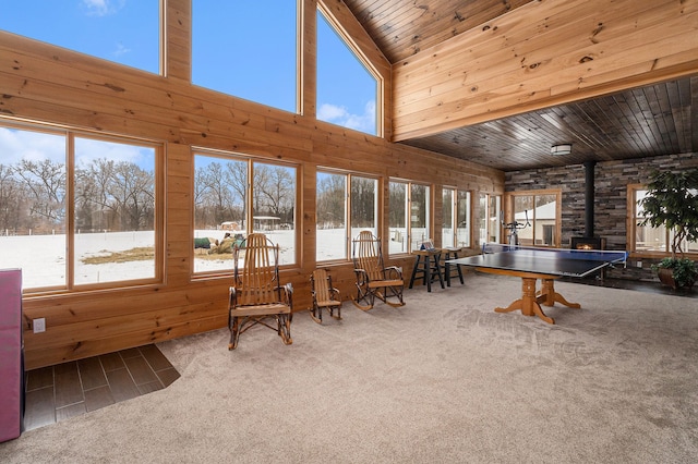 unfurnished sunroom with wood ceiling, a wealth of natural light, and a wood stove