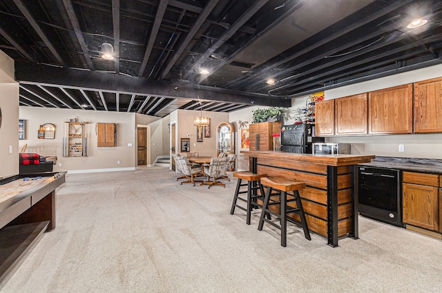 kitchen with dark countertops, baseboards, light carpet, brown cabinetry, and a breakfast bar