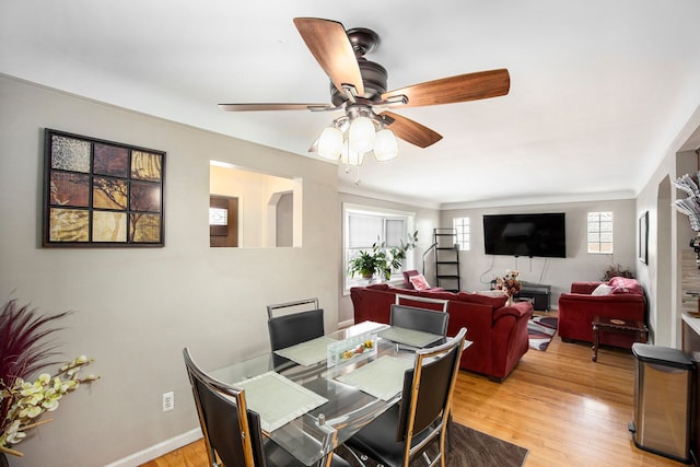 dining space featuring a ceiling fan, baseboards, and light wood finished floors