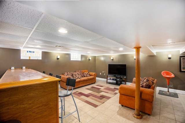 living room with visible vents, baseboards, a drop ceiling, and light tile patterned flooring