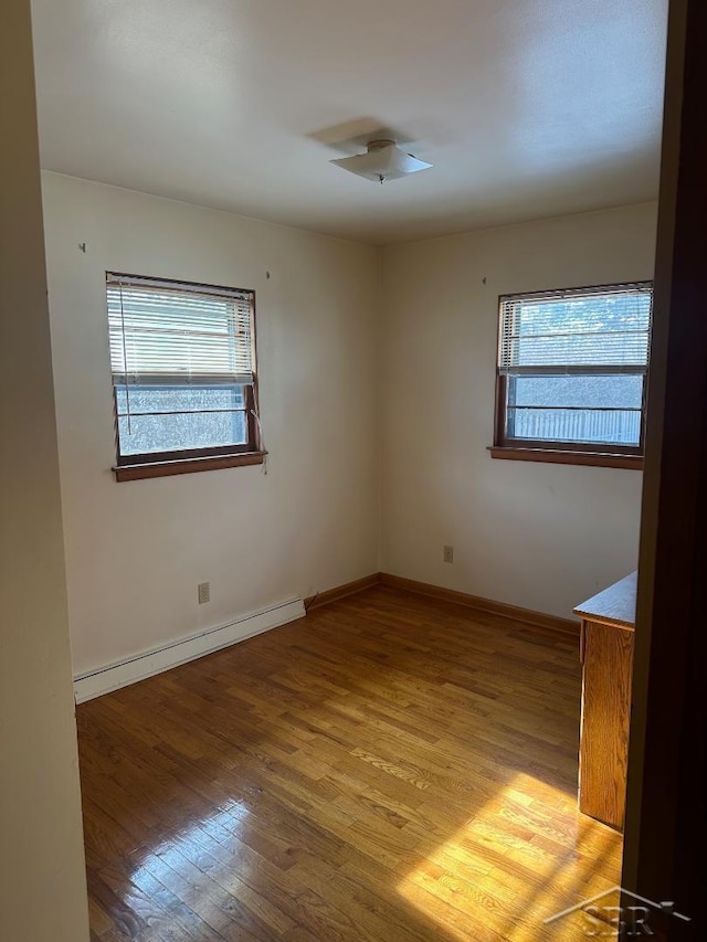 spare room with a baseboard radiator, a wealth of natural light, and light wood-type flooring