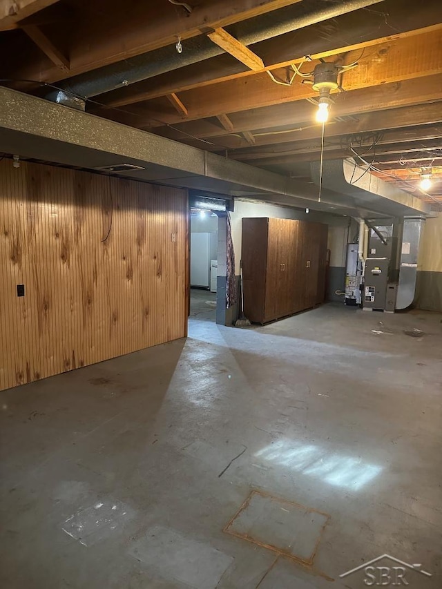 basement featuring wooden walls, heating unit, and gas water heater