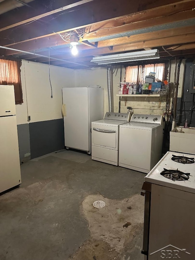 basement with white refrigerator, washing machine and clothes dryer, and sink