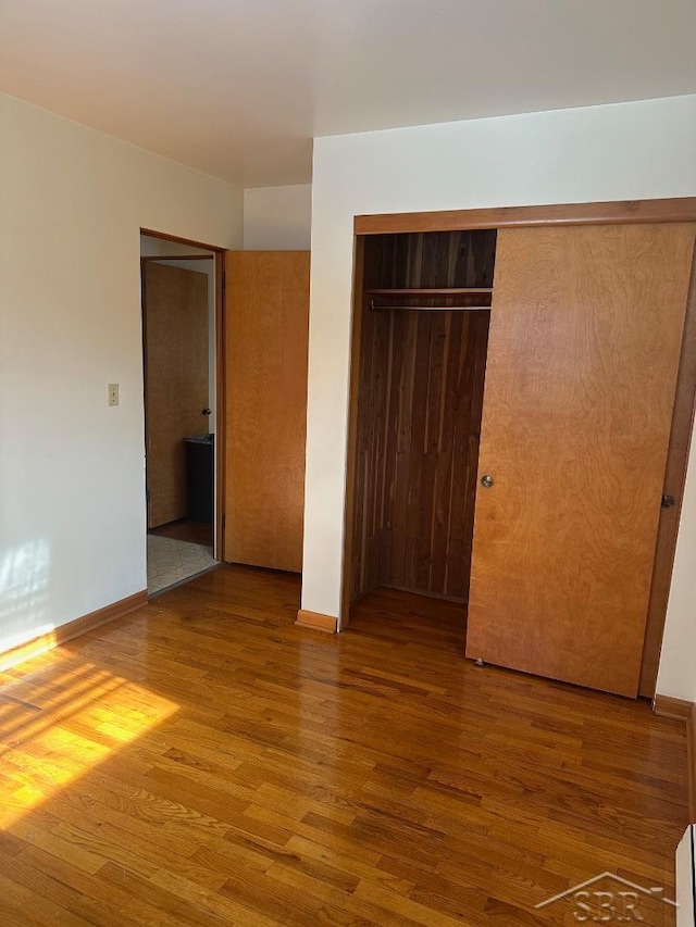 unfurnished bedroom with wood-type flooring and a closet