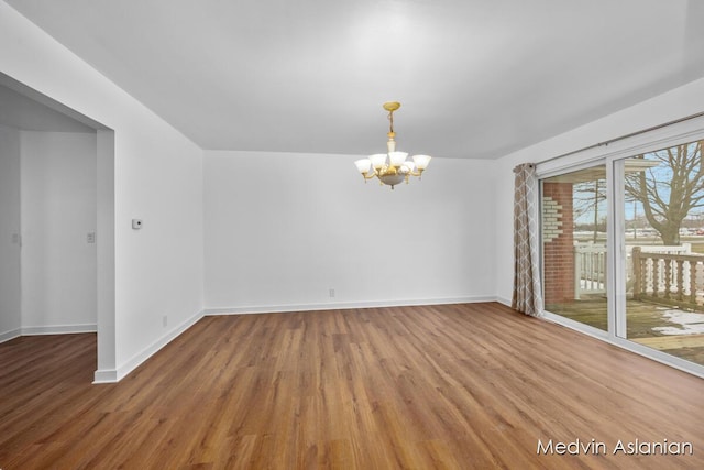 empty room featuring hardwood / wood-style flooring and a notable chandelier