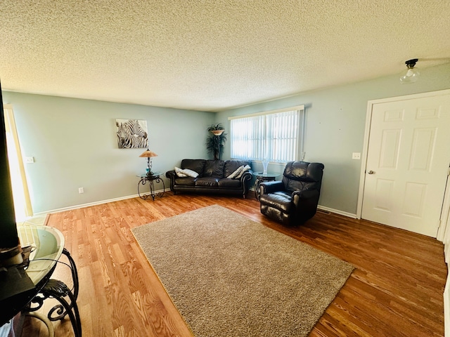 living room featuring a textured ceiling, baseboards, and wood finished floors