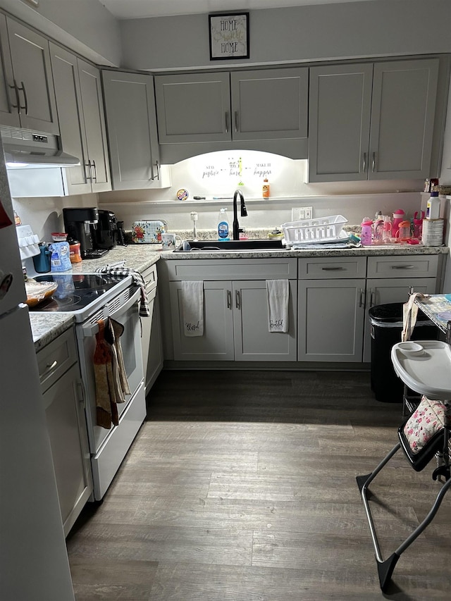 kitchen featuring white electric range, sink, light stone counters, light wood-type flooring, and stainless steel refrigerator