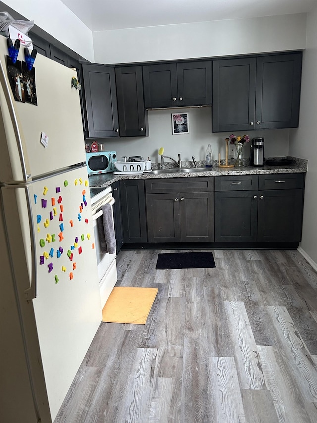 kitchen featuring white electric stove, sink, refrigerator, and light wood-type flooring