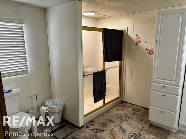 bathroom featuring a shower with door, a textured ceiling, and toilet