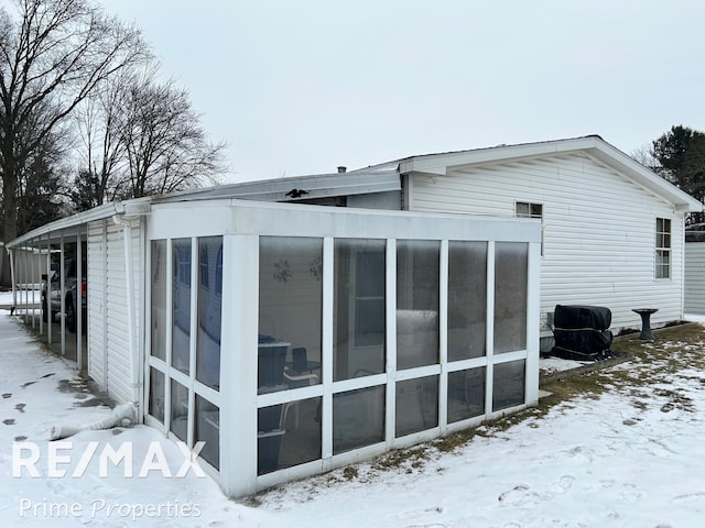 snow covered property featuring a sunroom