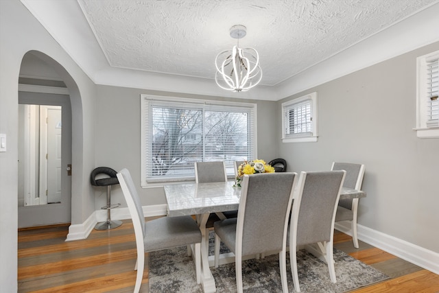 dining space featuring hardwood / wood-style floors, a textured ceiling, and a chandelier