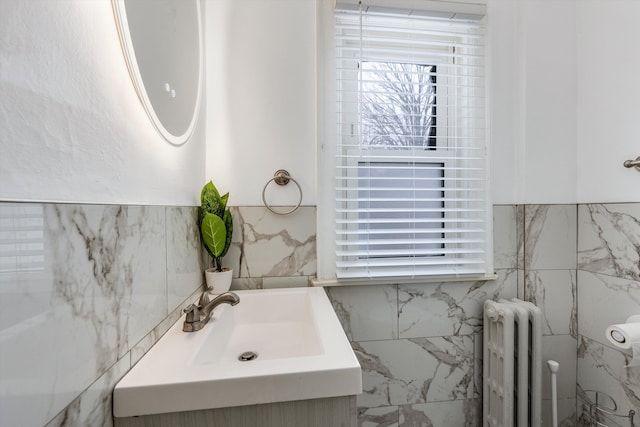 bathroom featuring vanity, radiator, and tile walls