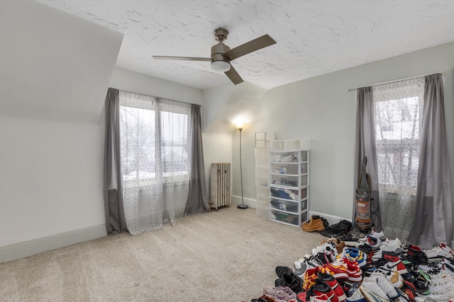 interior space with ceiling fan, radiator heating unit, a textured ceiling, and carpet