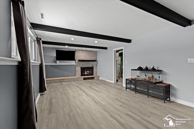 living room featuring beamed ceiling, a fireplace, and light hardwood / wood-style flooring