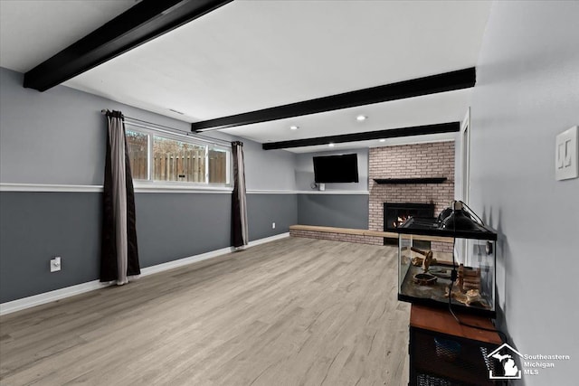 living room featuring beam ceiling, a fireplace, and light wood-type flooring