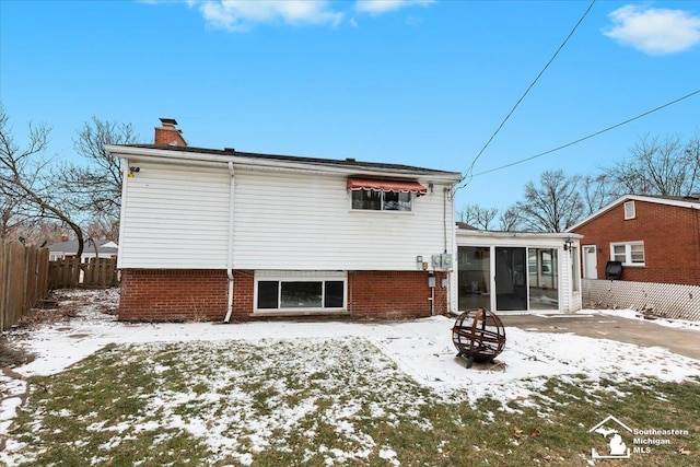 snow covered rear of property featuring a fire pit