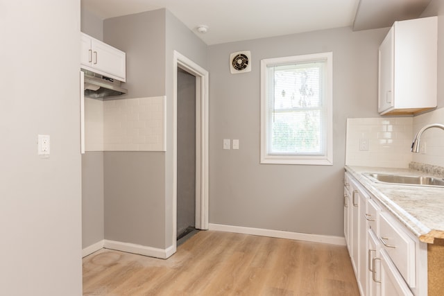 kitchen featuring sink, backsplash, light hardwood / wood-style floors, and white cabinets