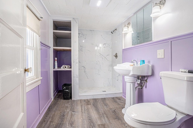 full bathroom with toilet, wood finished floors, a marble finish shower, and a decorative wall