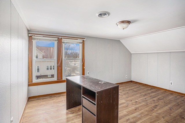 unfurnished office with light wood-type flooring, visible vents, and vaulted ceiling