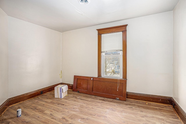 unfurnished room with light wood-style floors, visible vents, and baseboards