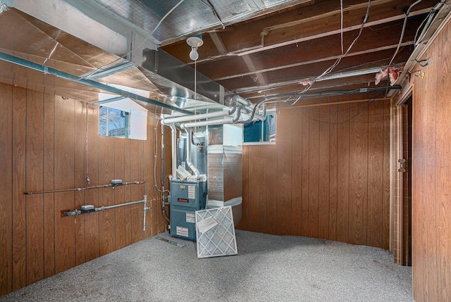 basement with carpet floors, wood walls, and heating unit