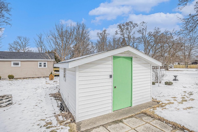 snow covered structure featuring an outbuilding and a storage shed