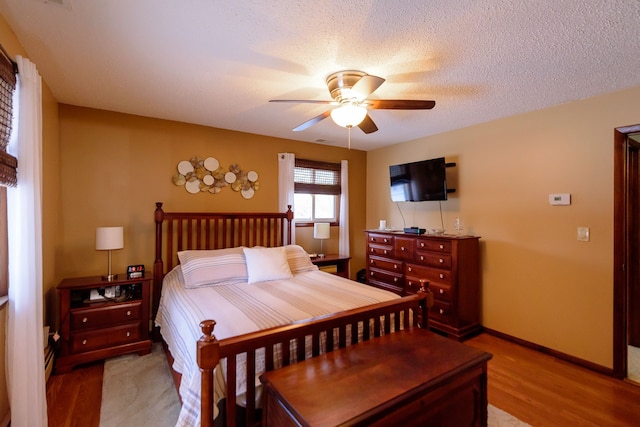 bedroom featuring light hardwood / wood-style floors, ceiling fan, and a textured ceiling