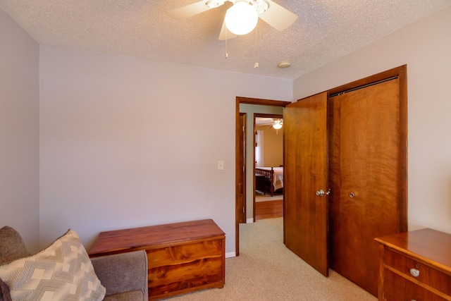 sitting room featuring a textured ceiling, ceiling fan, and light colored carpet