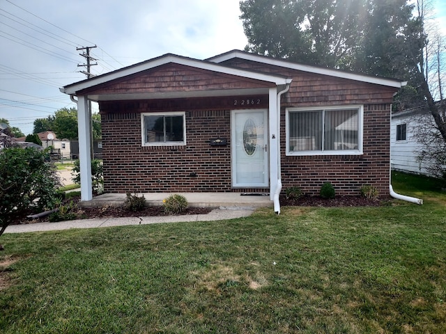 bungalow-style house featuring brick siding and a front yard